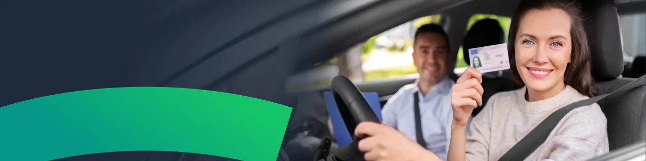 Uśmiechnięta młoda kobieta odbierająca prawo jazdy w samochodzie egzaminacyjnym po zdanym egzaminie państwowym 2026